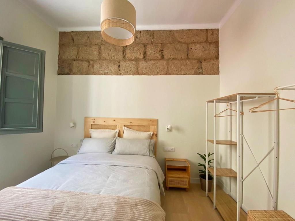 a bedroom with a bed and a brick wall at La Puebla Rooms in Teror