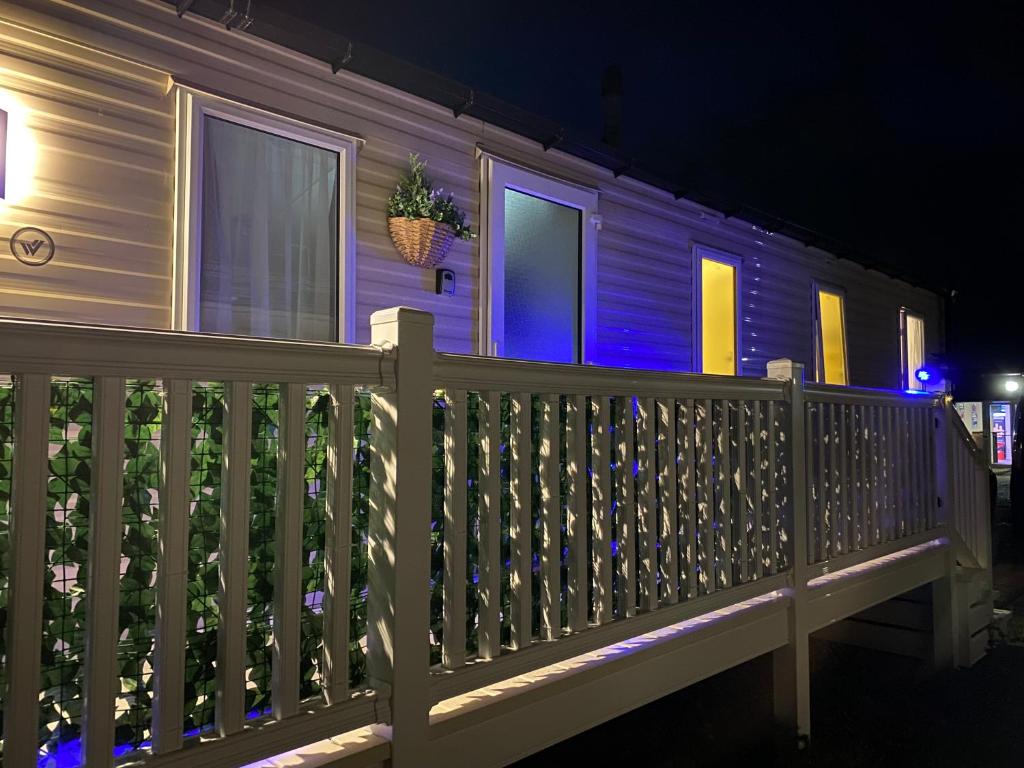 a house with blue lights on a wooden fence at Comfy Cosy Caravan_Romney Sands in Littlestone-on-Sea