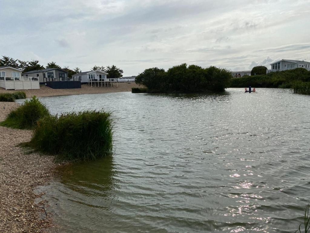 a large body of water with houses and grass at Comfy Cosy Caravan_Romney Sands in Littlestone-on-Sea