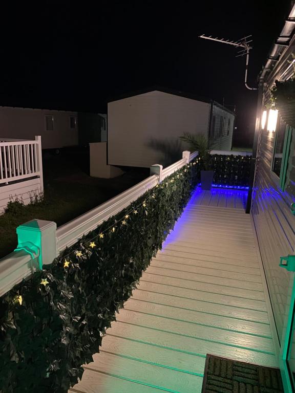 a walkway lit up at night with blue lights at Comfy Cosy Caravan_Romney Sands in Littlestone-on-Sea