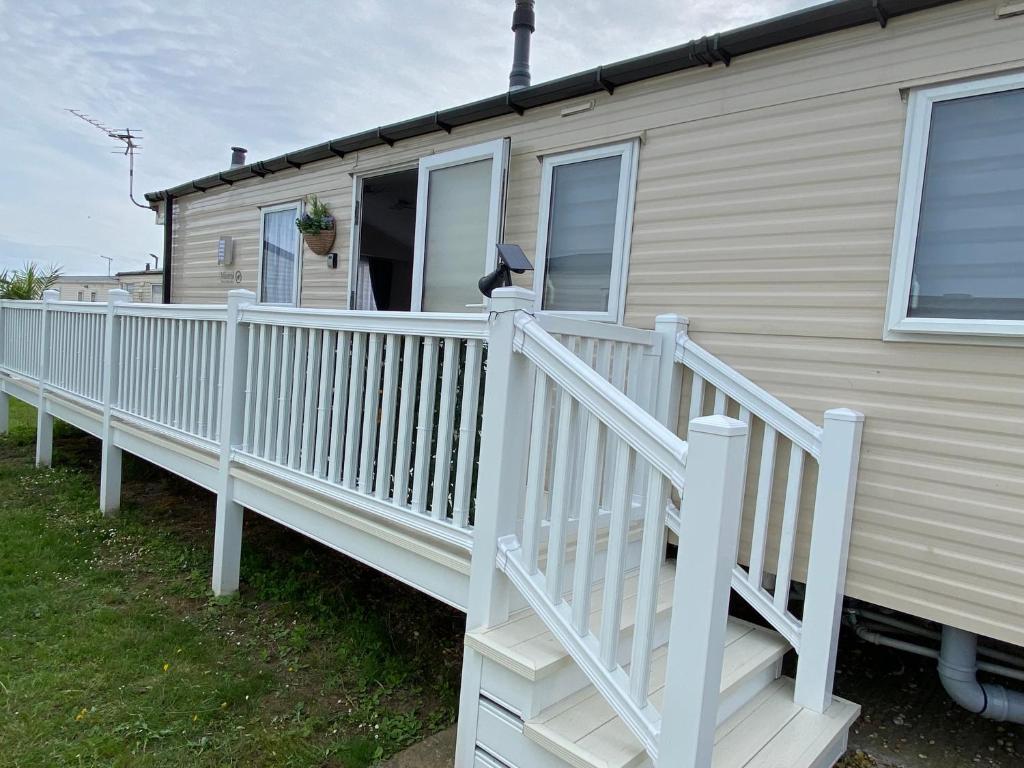a white railing on a house with a porch at Comfy Cosy Caravan_Romney Sands in Littlestone-on-Sea