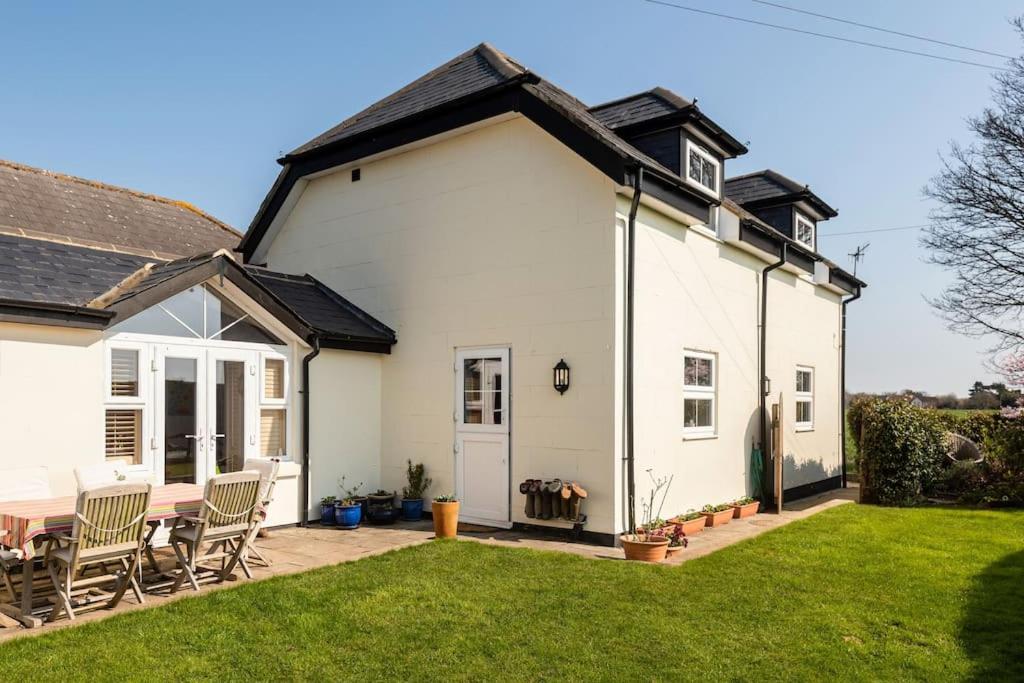 a white house with chairs and a table in a yard at Woodfield Wellbeing in Oving