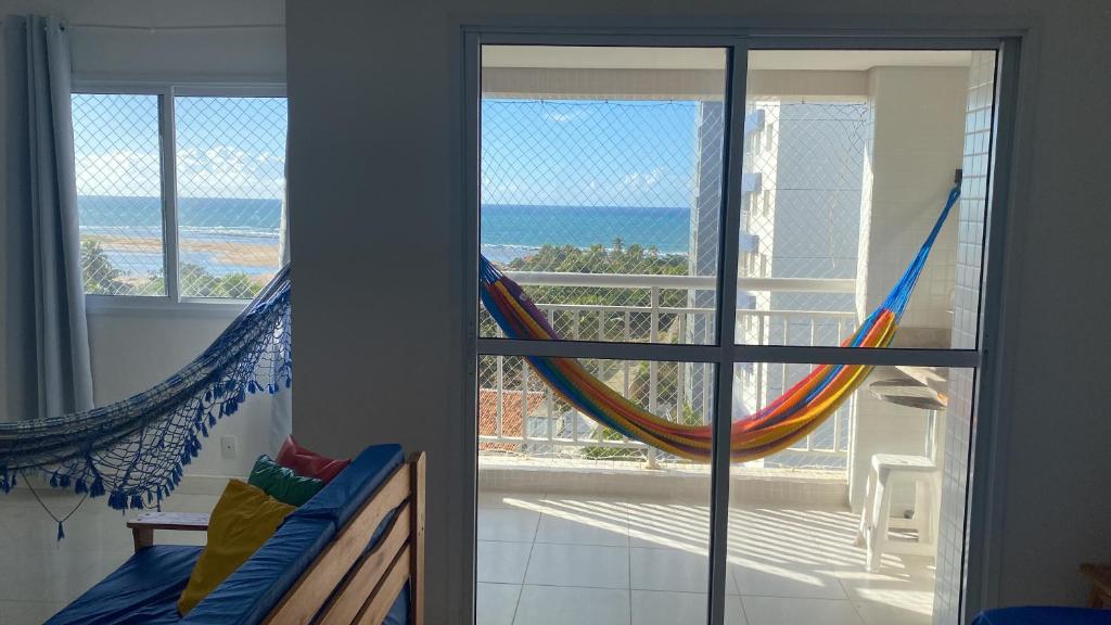 a room with a view of the ocean and a hammock at Apt agradabilíssimo vista mar in Lauro de Freitas