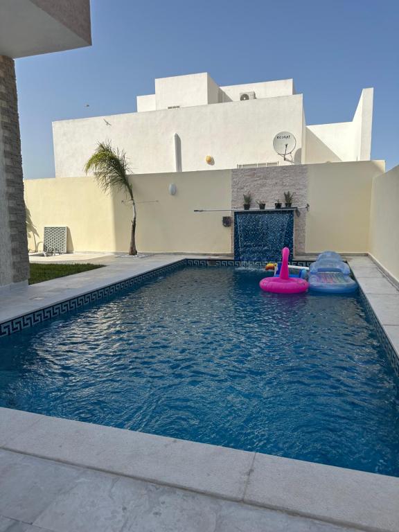 uma piscina com um carro alegórico cor-de-rosa num edifício em Magnifique villa vue mer em El Mida