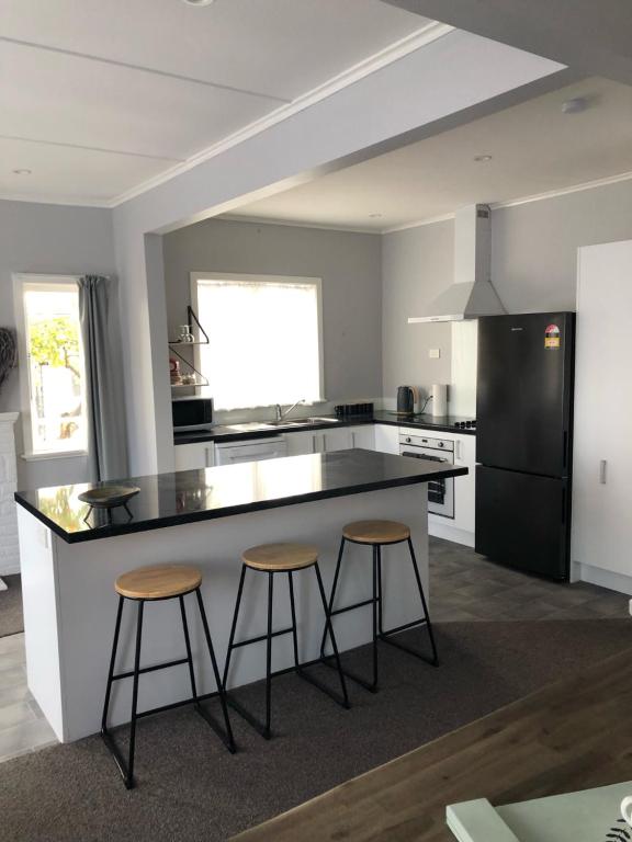 a kitchen with a black and white counter and stools at Nights on Broadway - THE HOUSE in Matamata