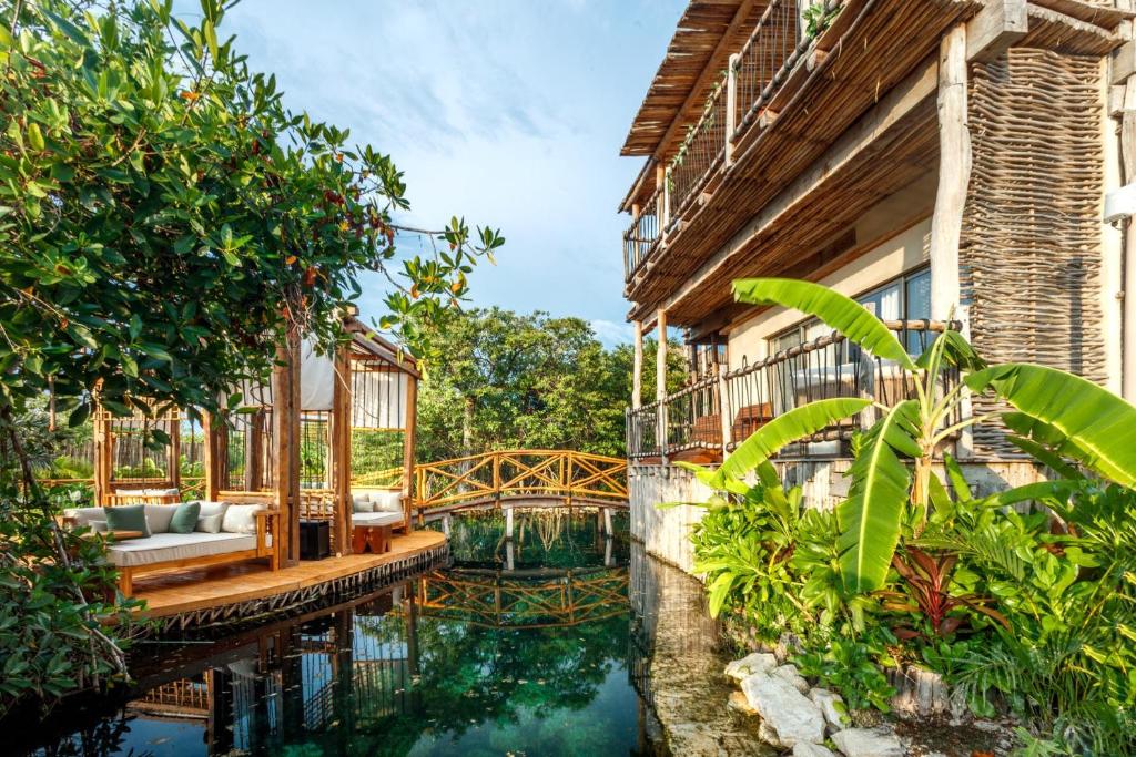 a house with a pond in front of a building at Hotel Shibari - Restaurant & Cenote Club in Tulum