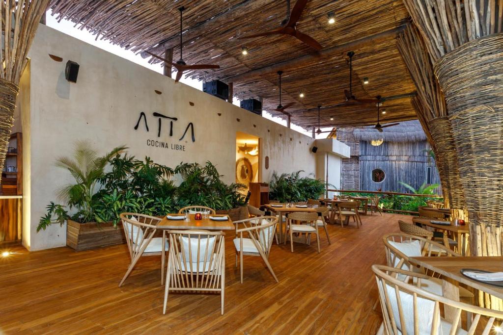 a restaurant with tables and chairs in a room at Hotel Shibari - Restaurant & Cenote Club in Tulum