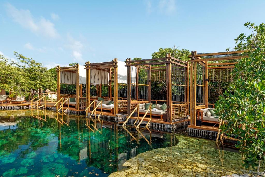 a resort with a pool with beds in it at Hotel Shibari - Restaurant & Cenote Club in Tulum