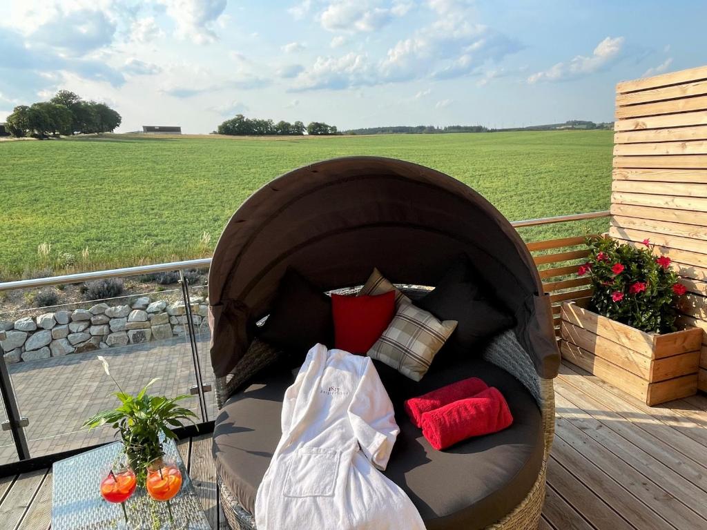 una silla en una terraza con vistas a un campo en Chalet-Ferienwohnung Giebeltraum, 115 qm, Wellness/Fitness/Sauna – Bergrödelhof en Feilitzsch