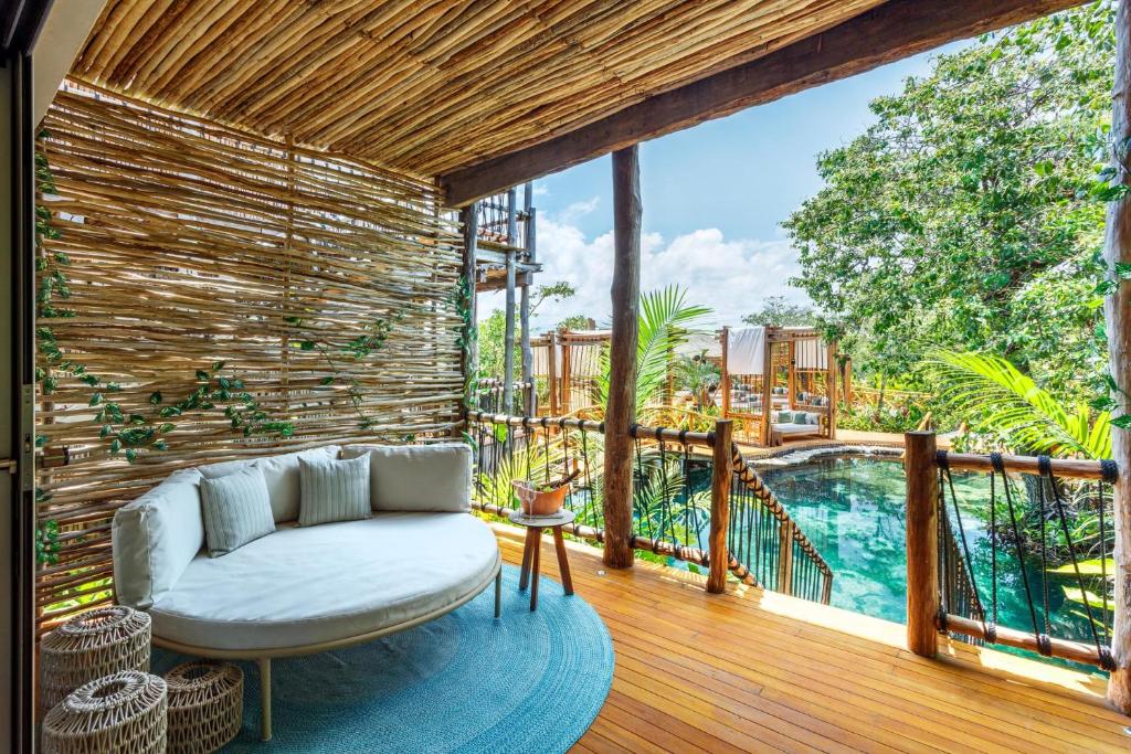 a living room with a couch on a deck with a pool at Hotel Shibari - Restaurant & Cenote Club in Tulum