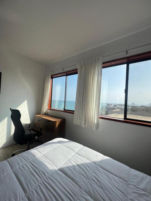 1 dormitorio con 1 cama, 1 silla y ventanas en Casablanca del Mar, en Punta Hermosa