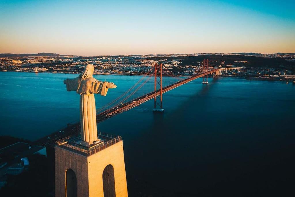 a statue of a cross with a bridge in the background at Lisbon Tagus River - Almada in Almada
