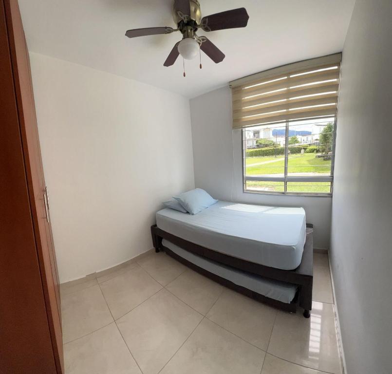 1 dormitorio con 1 cama, ventilador de techo y ventana en Espectacular apartamento Conjunto Piedemonte, en Villavicencio