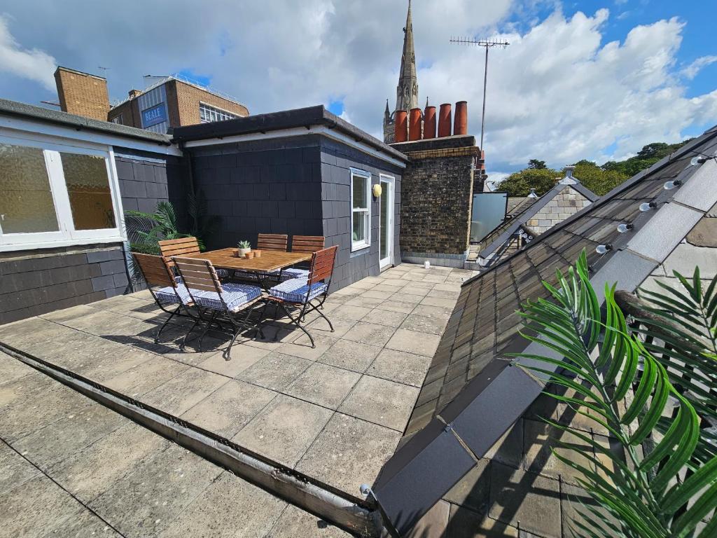 eine Terrasse mit einem Tisch und Stühlen auf einem Haus in der Unterkunft Cityscape Haven: 1 Bedroom Apartment with Terrace and City view in Bournemouth
