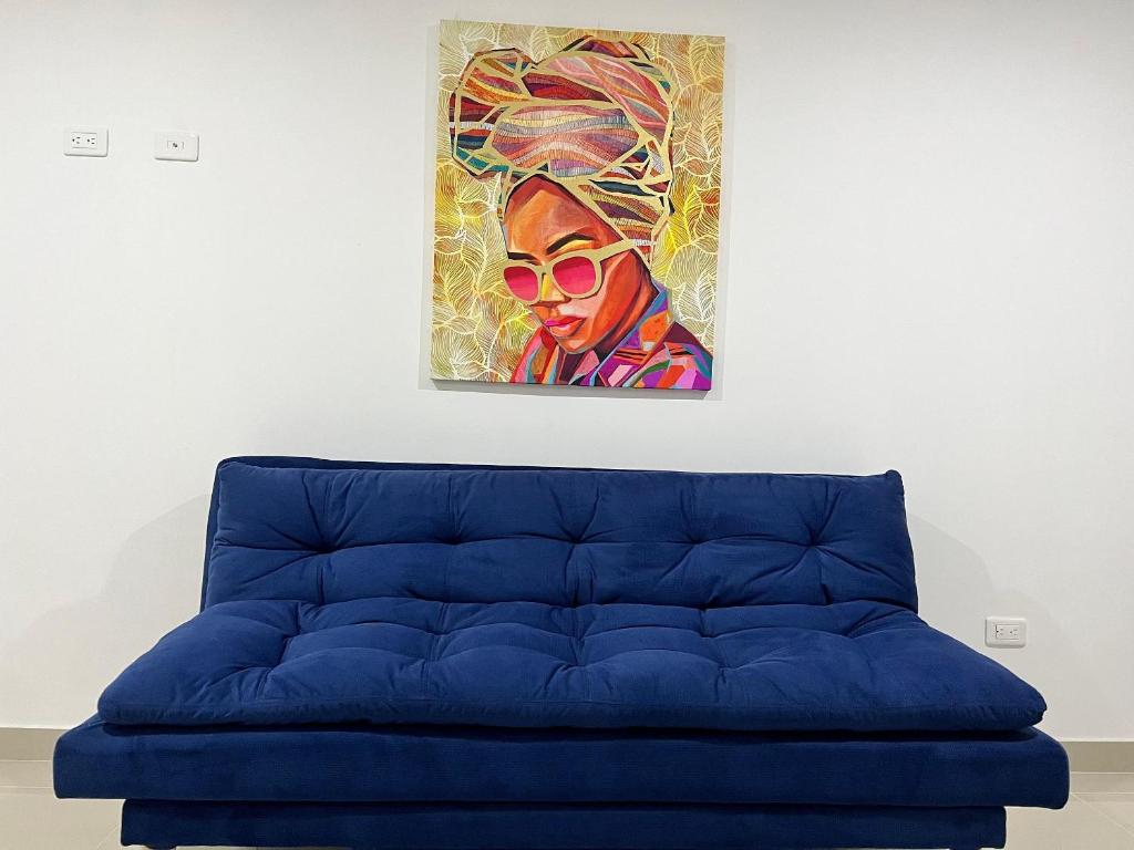 un divano blu in una stanza con un dipinto sul muro di Río Guatapuri y Confort Deluxe a Valledupar