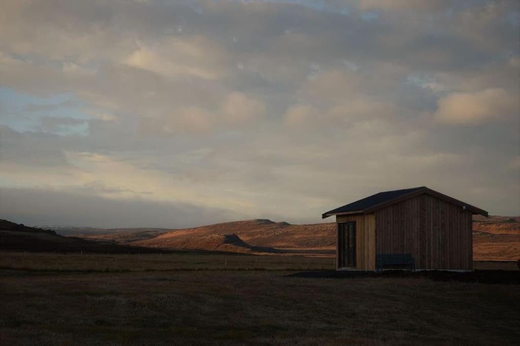 ein kleiner Schuppen auf einem Feld mit Bergen im Hintergrund in der Unterkunft Stóri-Bakki cosy cottage near Egilsstaðir-Jökull in Stóri-Bakki