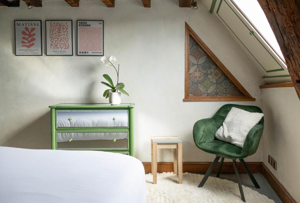 a bedroom with a green chair and a table at Suite Toussaint - Calme &amp; Authentique in Angers
