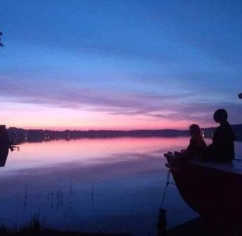 2 personnes assises sur un quai donnant sur un lac dans l'établissement Apartament Syrenka przy jeziorze Czos, à Mrągowo