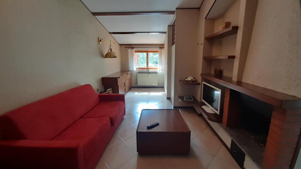 sala de estar con sofá rojo y chimenea en La Tana di Tina en Pescocostanzo