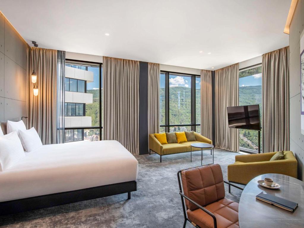 a bedroom with a bed and a living room at Pullman Tbilisi Axis Towers in Tbilisi City