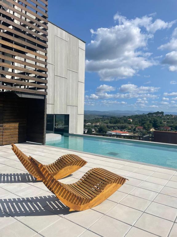 a pool with two lounge chairs on top of a building at Puro Dão Hotel & Spa in Nelas