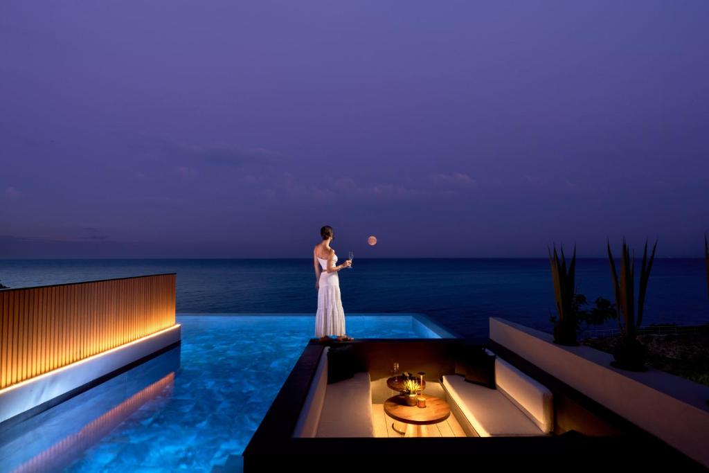 Una mujer con un vestido blanco parada junto a una piscina en SEA ZANTE Luxury Beachfront Retreat en Tragaki