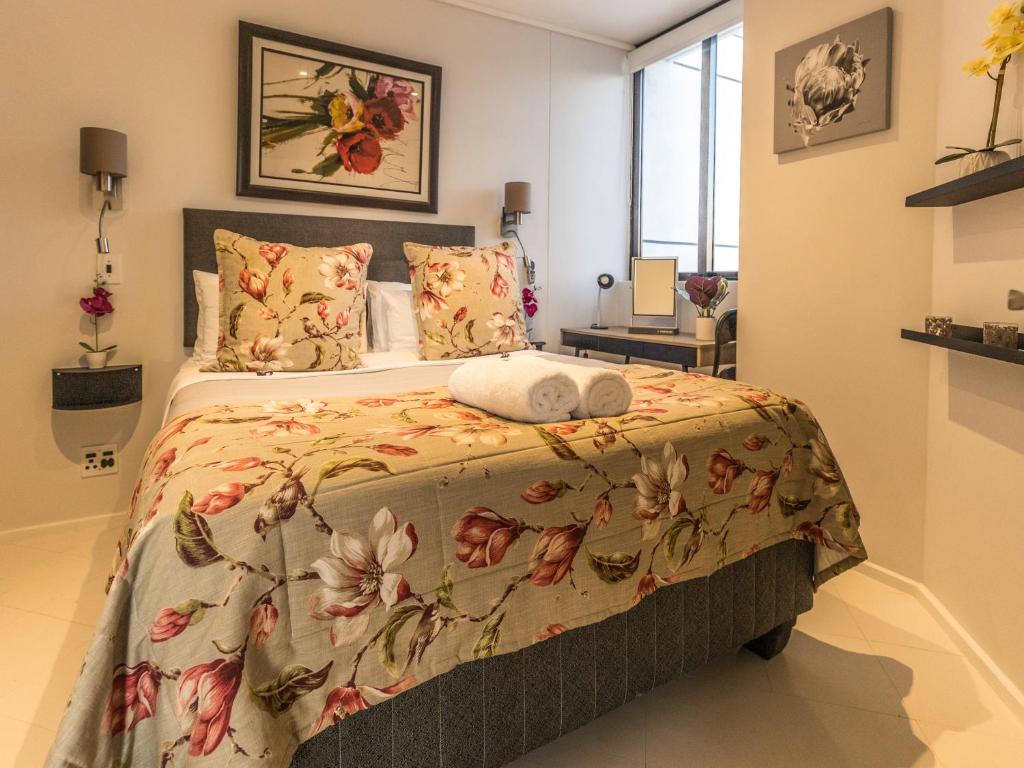 1 dormitorio con 1 cama con colcha de flores en Flamingo Sea Point Sea View Luxury Best Position 1 Bedroom Apartment Queen Size Bed & Inverter For TV, en Ciudad del Cabo