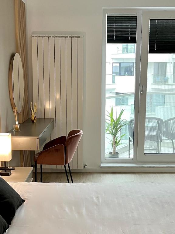 a bedroom with a bed and a chair and a window at Elite Summer Suite in Năvodari