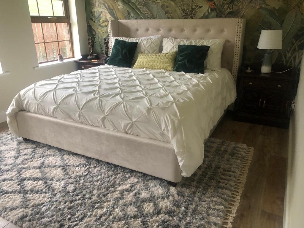 The Fairways, CastleBlayney في كاستلبلايناي: سرير أبيض كبير في غرفة نوم مع سجادة