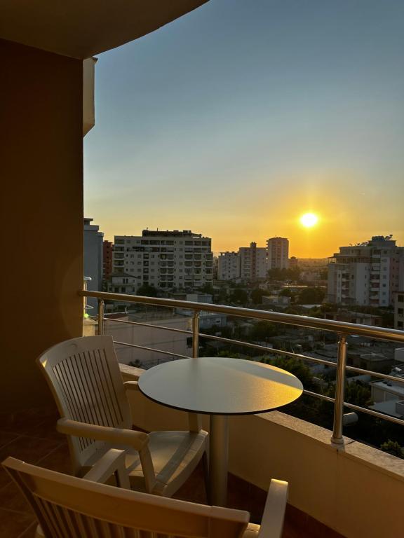 a table and chairs on a balcony with a sunset at AMI apartament in Vlorë