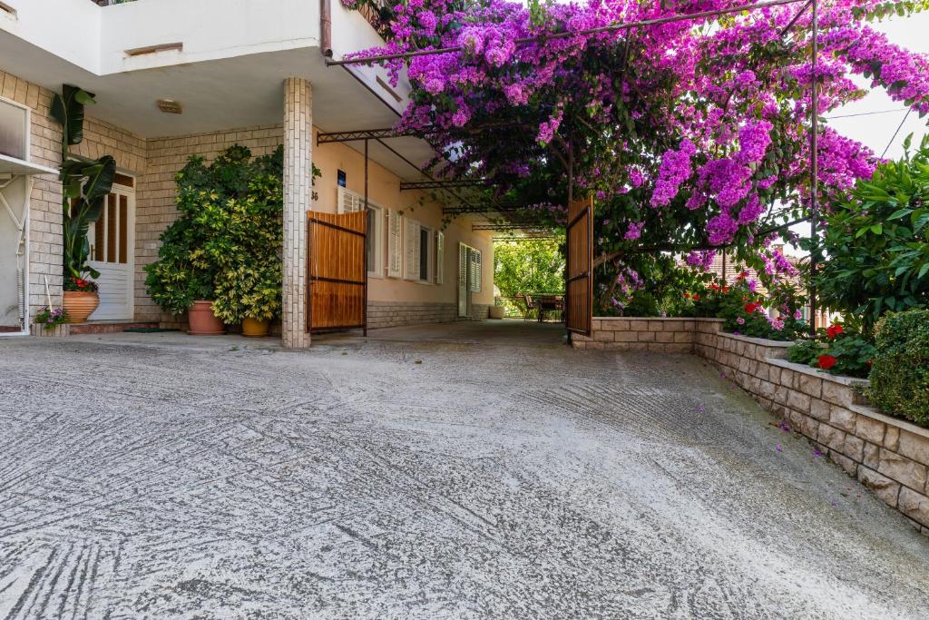 an empty courtyard with purple flowers on a building at Apartments by the sea Sumpetar, Omis - 949 in Jesenice