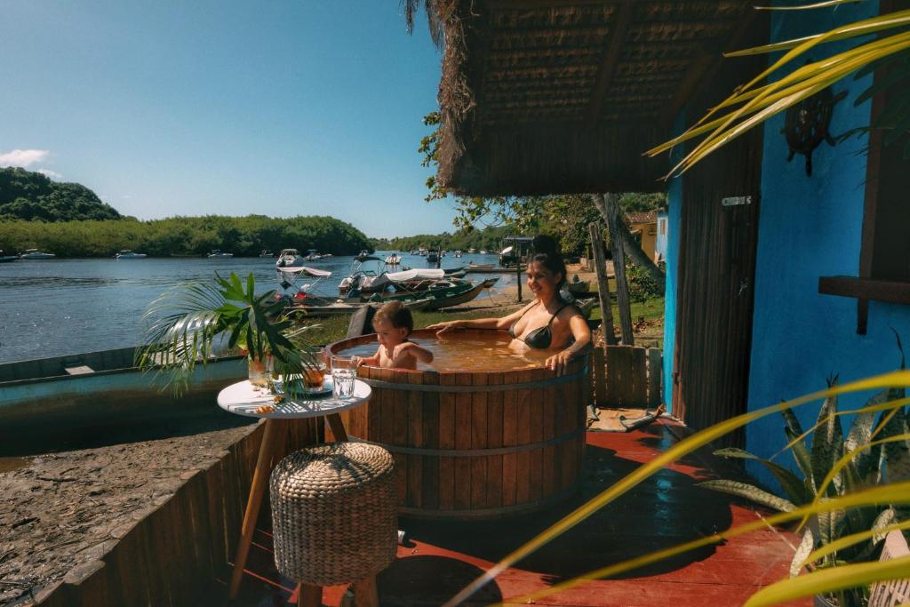 um homem e um rapaz numa banheira de hidromassagem ao lado de um rio em Casinha Azul Caraíva - casa completa na beira do Rio em Caraíva