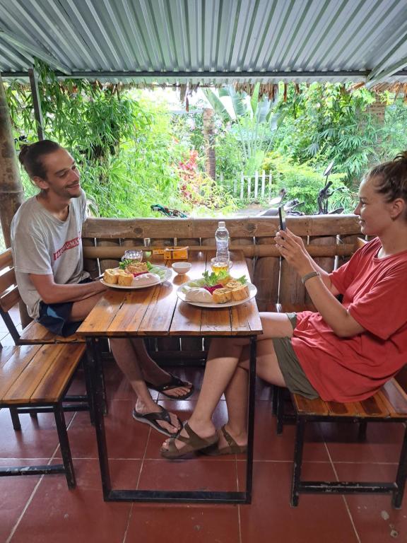 a man and woman sitting at a table with food at Homestay field in Ha Giang