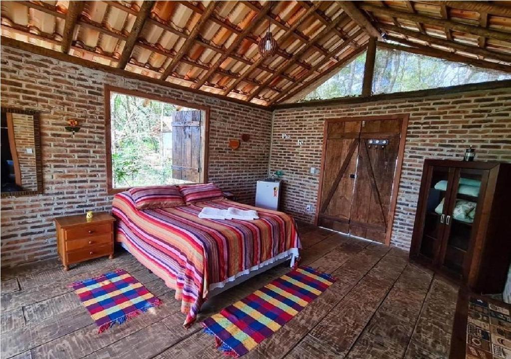 una camera con letto e muro di mattoni di Chalé Rústico 3 - Retiro Andaluz a Brumadinho