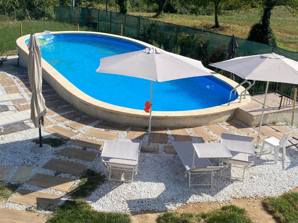 a swimming pool with two umbrellas and chairs next to it at Orlandi Sun casa 2 in Sarnano