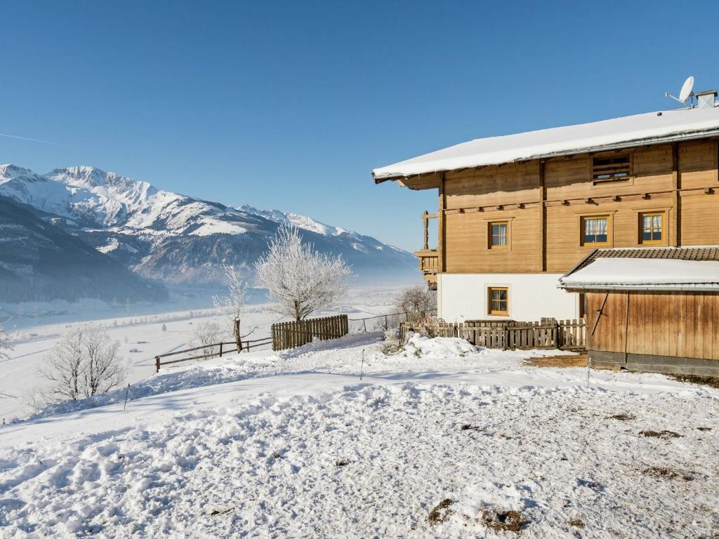 a wooden house in the snow with mountains in the background at Apartment Uttendorf near Ski Lift in Uttendorf
