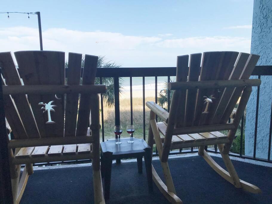 two rocking chairs sitting on a balcony with wine glasses at Flip Flop at Compass Cove in Myrtle Beach