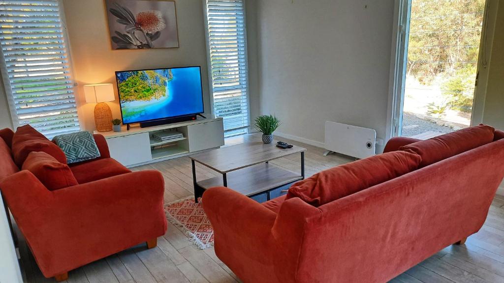 a living room with two red chairs and a television at River-Tide Retreat in American River
