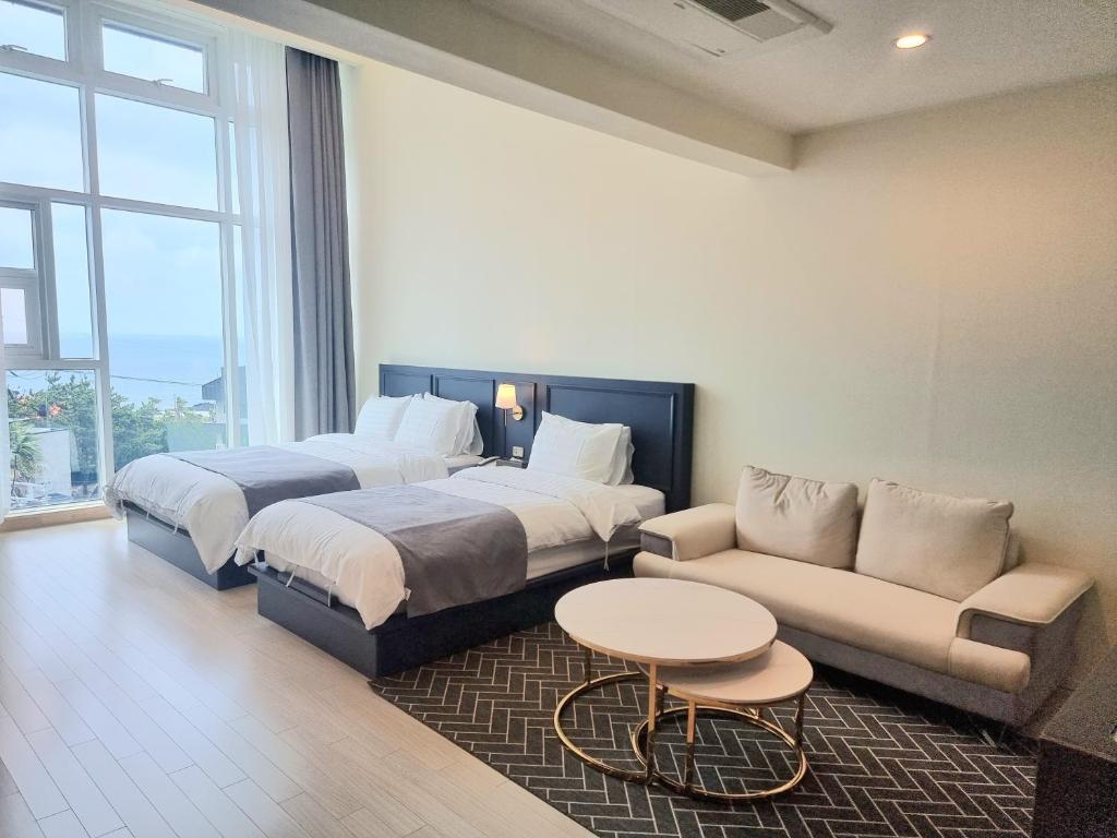 um quarto de hotel com duas camas e um sofá em Rich Hotel em Jeju