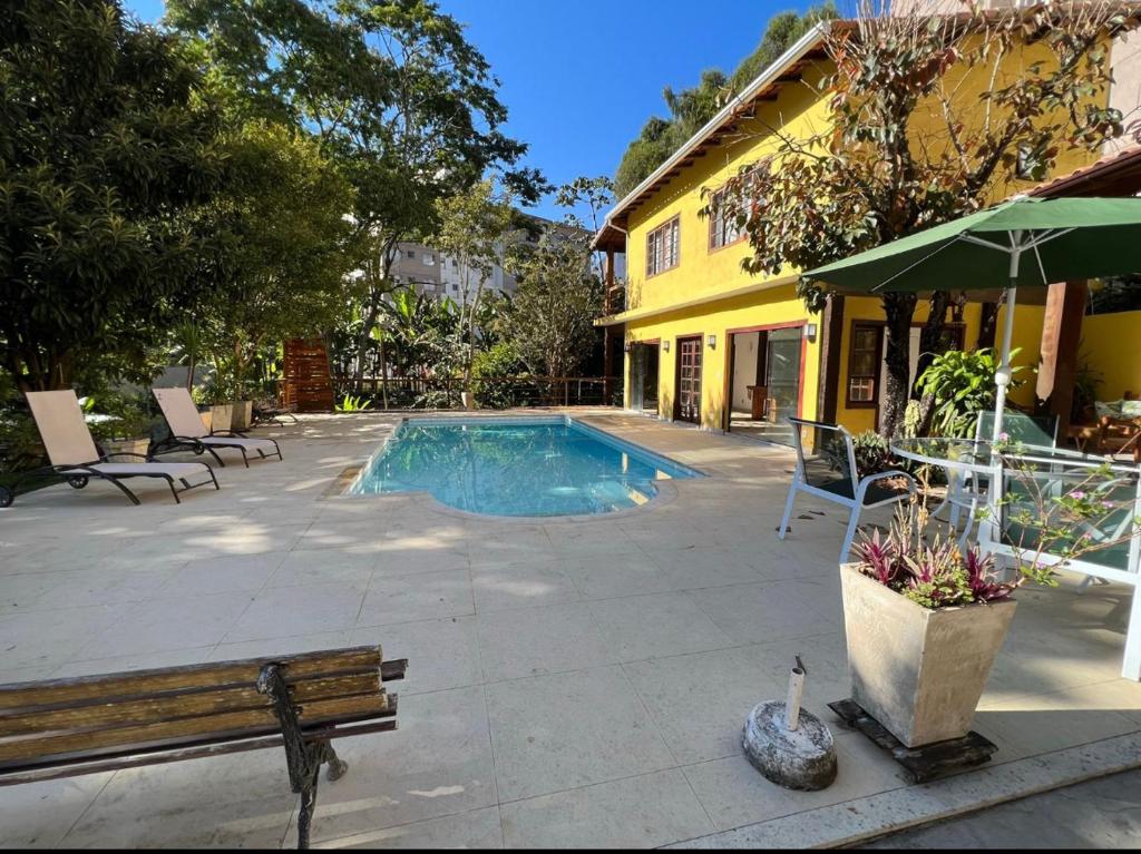 a swimming pool with a bench next to a building at Villa Aconchego Corrêas Itaipava in Petrópolis