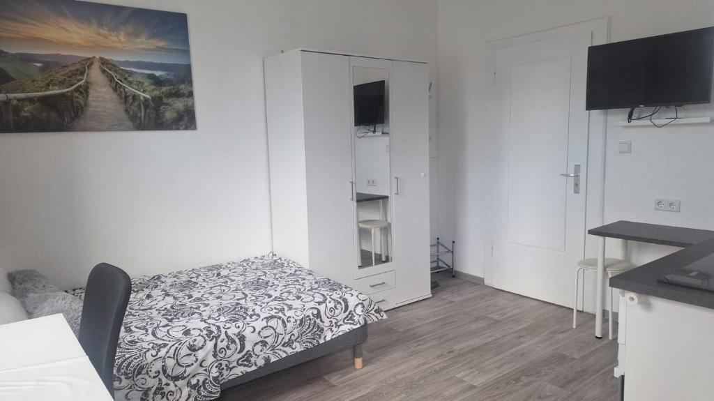 Studio Apartment mit Balkon 18 في إيسن: غرفة بيضاء صغيرة مع سرير وخزانة