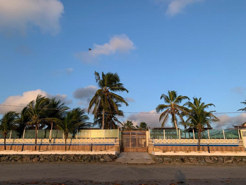 a fence with palm trees in the background at Casa de Praia Panaquatira - São J. Ribamar in São-José-do-Ribamar