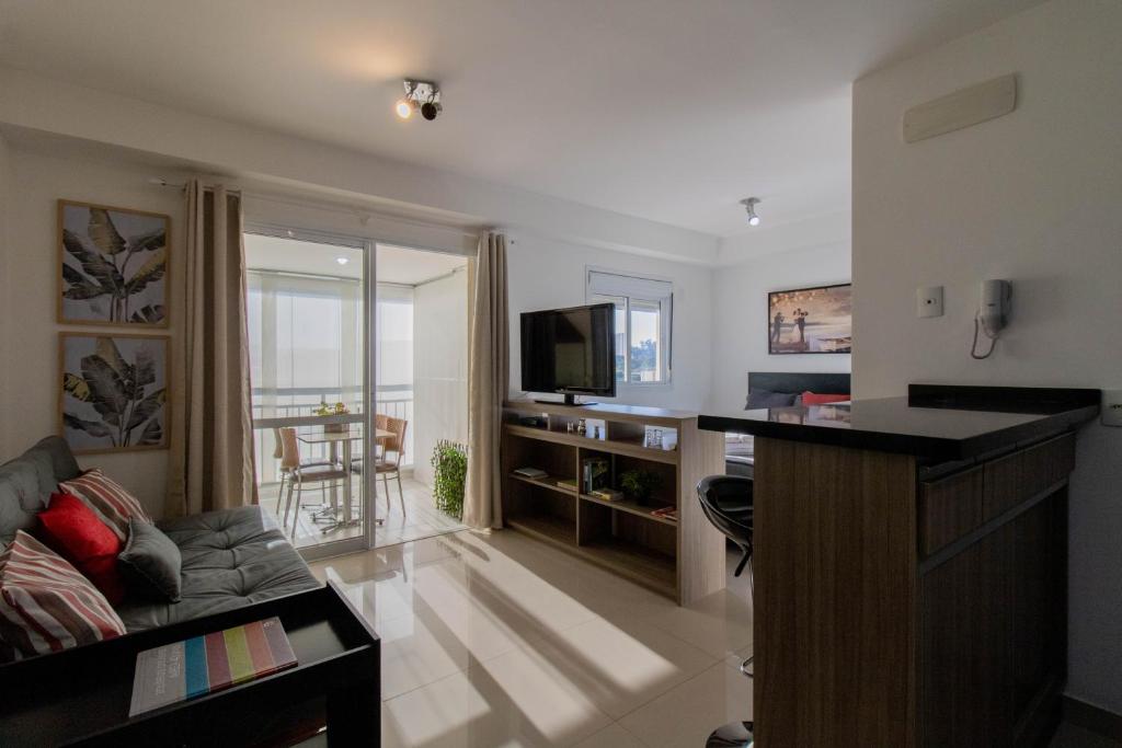Sunset Studio - GRU في جوارولوس: غرفة معيشة مع أريكة وتلفزيون بشاشة مسطحة