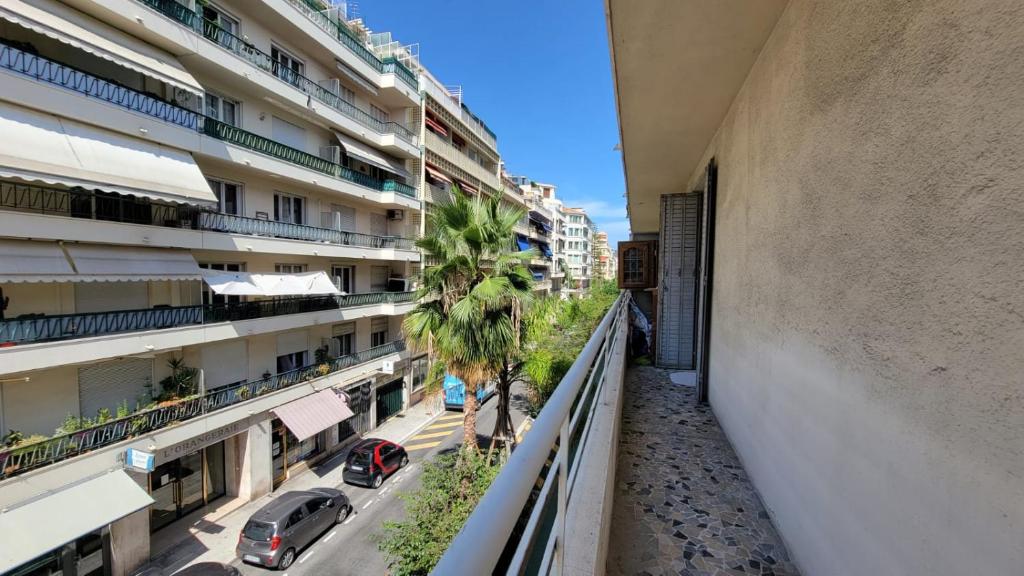 an apartment balcony with a palm tree and buildings at New two bedroom apartment with AC by the sea in Nice