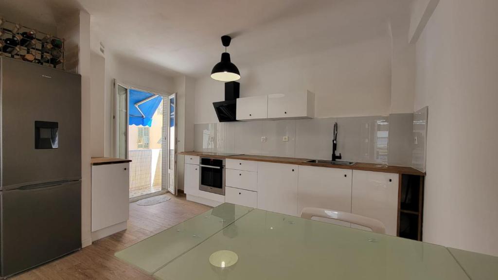 a kitchen with white cabinets and a glass table at New two bedroom apartment with AC by the sea in Nice
