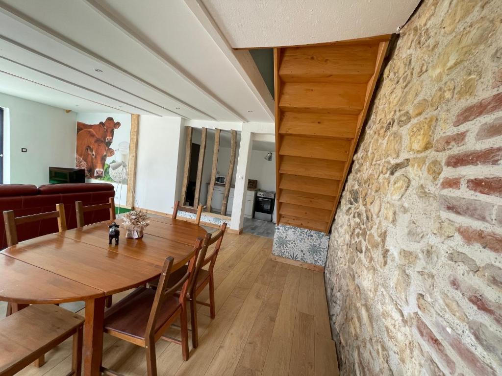 una sala da pranzo con tavolo e parete in pietra di Gîte chez Line & Mon a Bournonville
