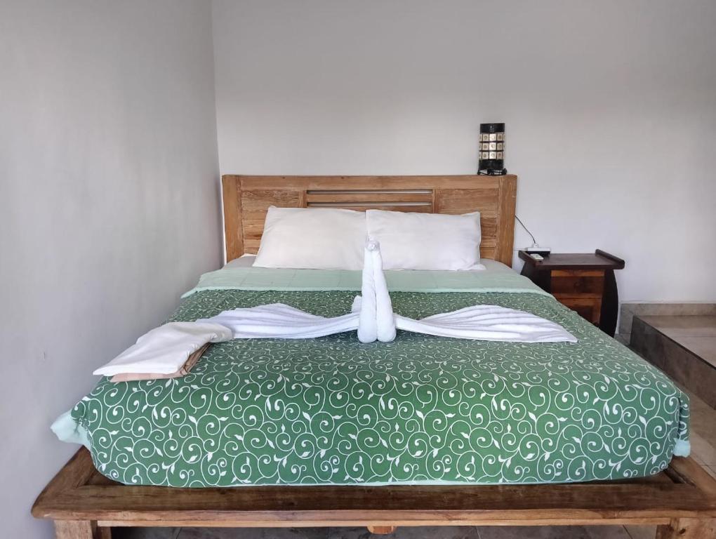 - un lit avec une couette verte et 2 serviettes dans l'établissement Lee Wong house 2, à Ubud