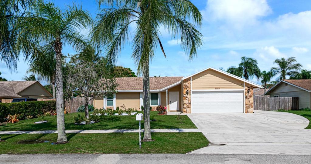 a house with palm trees in front of a driveway at Beautiful Home Away From Home in Royal Palm Beach