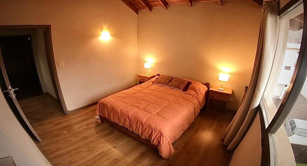 a small bedroom with a bed and two lamps at Depto Elordi in San Martín de los Andes