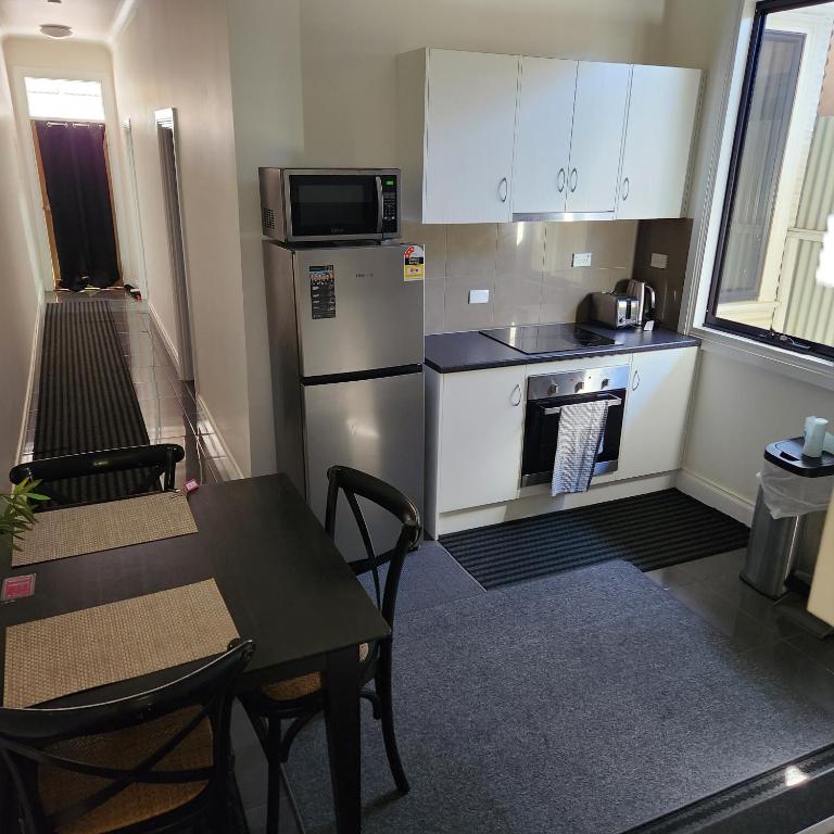 布罗肯希尔City Villa 41 Blende st Broken Hill NSW 2880的厨房配有冰箱、桌子和微波炉
